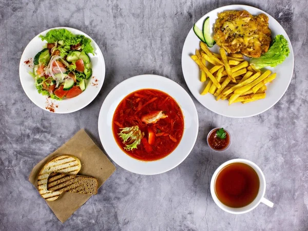 Borş, salata, et ve patatesle üç çeşit öğle yemeği.