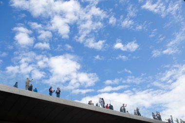 İnsanlar gökyüzüne karşı köprüde duruyor.