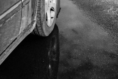 Bir araba tekerleği su birikintisine yansır.