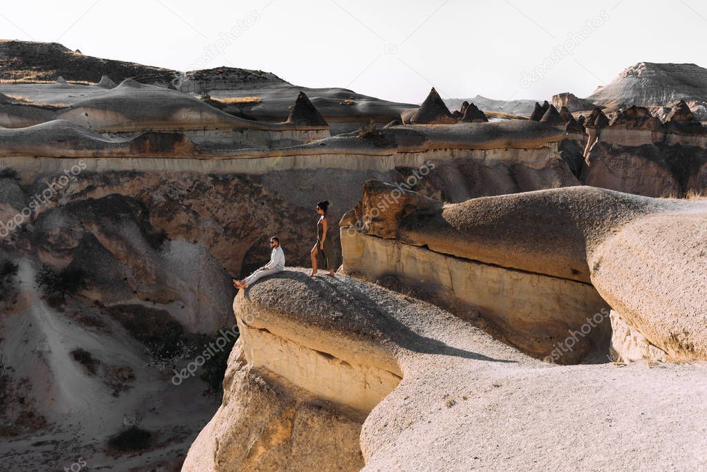 Couple in love in the mountains at sunset. Wedding trip the newlyweds. Tourists on the tour. A couple in love travels to Turkey, Cappadocia. Man and woman at sunset. Couple on the edge of the cliff