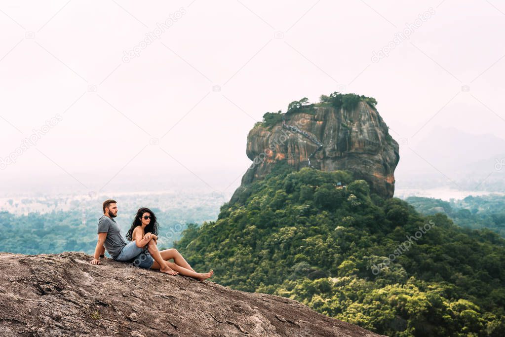 A couple in love on a rock admires the beautiful views. Boy and girl on the rock. A couple in love travels. Couple in Sri Lanka. Honeymoon in Asia. Man and woman in Sigiriya. Couple in the mountains