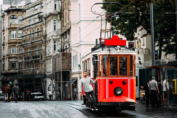 Istanbul'da Taksim Istiklal Caddesi'nde bir vintage tramvay adam. Adam toplu taşıma. Istiklal Caddesi, Türkiye'de eski Türk Tramvayda. Bir şehir sokak poz genç gülümseyen bir adam portresi.