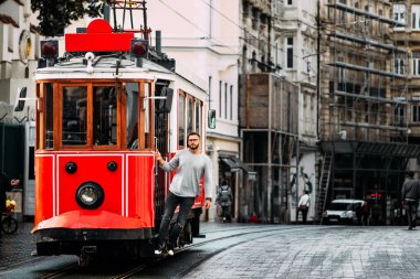 Istanbul'da Taksim Istiklal Caddesi'nde bir vintage tramvay adam. Adam toplu taşıma. Istiklal Caddesi, Türkiye'de eski Türk Tramvayda. Bir şehir sokak poz genç gülümseyen bir adam portresi.