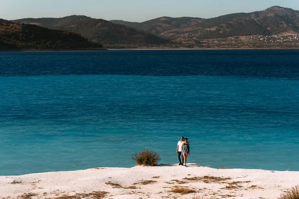 一对恋爱中的夫妇看着蓝色的泻湖 一对恋爱中的情侣在海滩上 蜜月爱好者 岛上的男人和女人 一对恋爱中的情侣在度假 男人和女孩拥抱 海上旅游 情侣旅行 — 图库照片