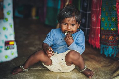 Yoksulluk, katta oturan eski yırtık kıyafetler, küçük bir yoksul Hintli kız resmini. Çikolata bebek