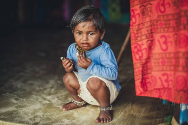 Yoksulluk, katta oturan eski yırtık kıyafetler, küçük bir yoksul Hintli kız resmini. Çikolata bebek