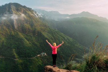 Kız dağlarda gündoğumu karşılar. Kız Sri Lanka seyahat. Dağ sporları. Atlet mutlu bitirmek. Dağ turizmi. Yürüyüş turu. Dağlara yolculuk. Batonlu yürüyüş. Arka görünüm