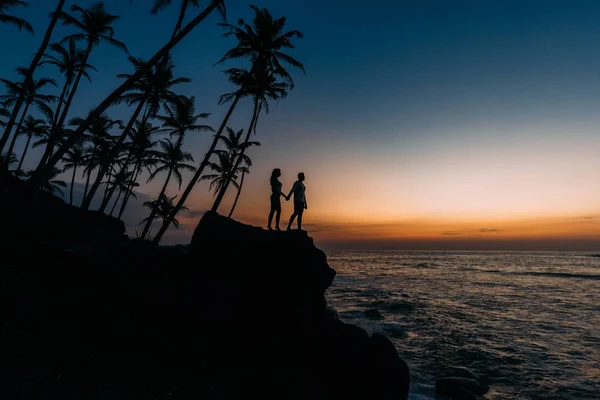 Silhouette of loving couple on sea. Man and woman at sunset. Honeymoon on the Islands. Man and woman meet sunset. Happy loving couple. Silhouette lovers. Wedding travel. Loving couple. Honeymoon trip