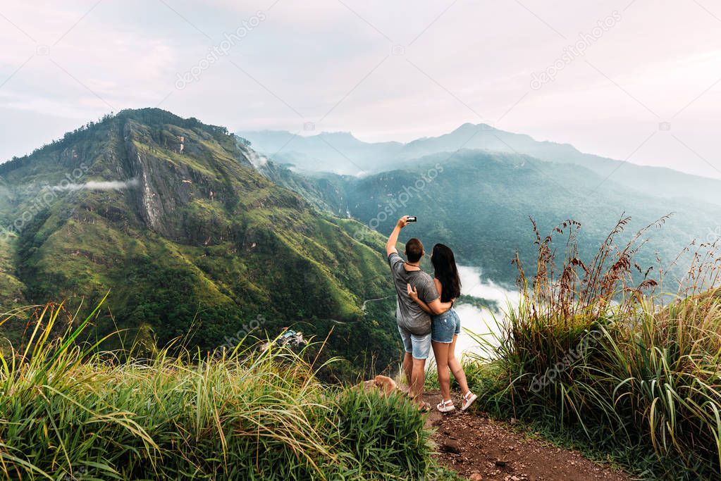 A couple in love takes a selfie. Man and woman holding hands. The couple travels around Asia. Travel to Sri Lanka. Honeymoon trip. Wedding travel. Tourists in the mountains. Dawn in the mountains