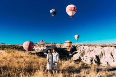 Türkiye, Kapadokya - 10 Ekim 2018: Balonların arasında aşık bir çift. Kapadokya 'daki mutlu çift. Dağlarda balayı. Erkek ve kadın seyahat ediyor. Balonla uçmak. Balon Festivali