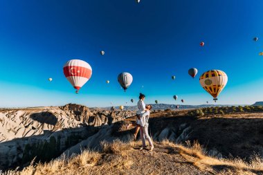 Kapadokya'da mutlu bir çift. Adam kıza evlenme teklif etti. Kapadokya'da balayı. Balon festivalinde bir çift. Balayı gezisi. Çift dünyayı dolaşıyor. Kapadokya Manzaraları