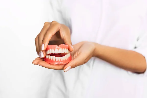 医師のクローズアップの手に歯科補綴 セラミック歯科橋を保持する歯科医 完全な入れ歯の正面図 歯科概念写真 人工歯科 入れ歯 — ストック写真