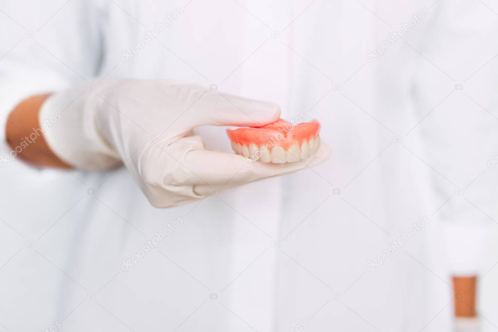 The dentist is holding dentures in his hands. Dental prosthesis in the hands of the doctor close-up. Dentistry conceptual photo. Prosthetic dentistry. False teeth. Removable denture
