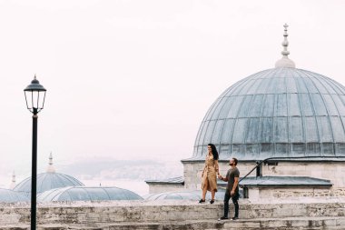 İstanbul'un çatılarında yürüyen çift. Mutlu çift Türkiye'ye seyahat ediyor. İstanbul'da dolaşan kadın ve erkek. Türkiye'de turistler. Doğu ülkesinde bir çift. Cami yakınında seyahat çift