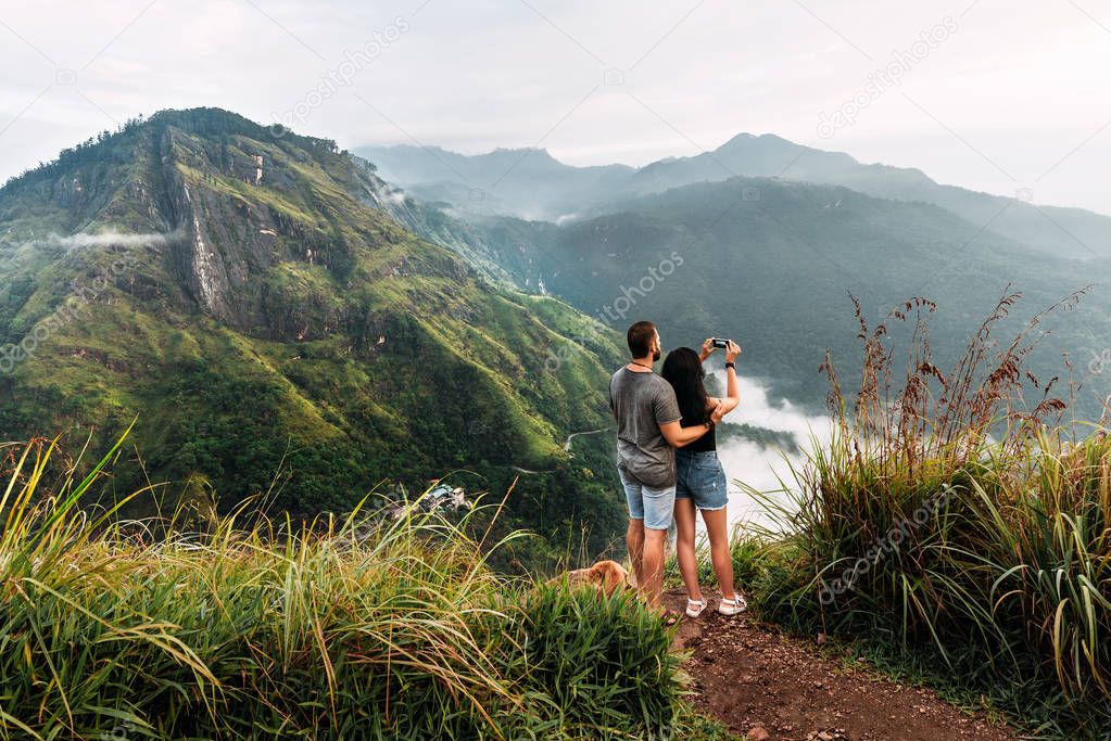 A couple in love travels to Sri Lanka. The couple travels the world. A man and a woman greet dawn in the Ella mountains, Sri Lanka. Travel to Asia.  The couple admires the beautiful scenery.