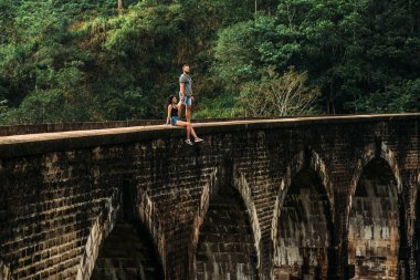 Tatilde aşık bir çift. Asya'yı dolaşan kadın ve erkek. Çift Sri Lanka'ya seyahat ediyor. Mutlu çift dünyayı dolaşır. Asya'daki gezginler. Takip et beni. Dokuz kemerli köprüde turistler