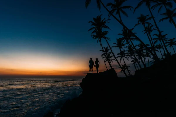 Silhouette of a couple in love on the beach. Man and woman at sunset. Honeymoon on the Islands. Man and woman meet sunset. Happy loving couple. Silhouette lovers. Honeymoon trip.  Hold hands