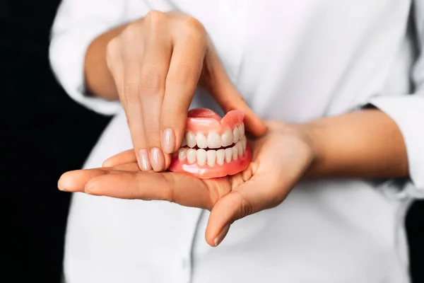歯医者は彼の手に入れ歯を持っている 医師の手の中に歯科補綴物を閉じる 完全な入れ歯の正面図 歯の概念写真 歯医者だよ — ストック写真