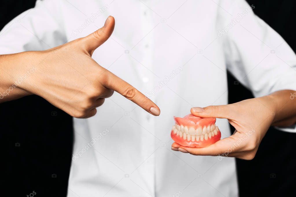 The dentist is holding dentures in his hands. Dental prosthesis in the hands of the doctor close-up. Front view of complete denture. Dentistry conceptual photo. Prosthetic dentistry. False teeth
