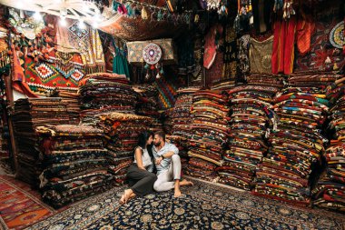 Kapadokya 'da yürüyen genç bir çift. Mağazadaki kadın ve erkek. Türkiye 'de aşık bir çift. Doğu ülkesindeki kadın ve erkek. Mutlu çift dünyayı geziyor. Halıları olan bir oda. Dükkanda turistler