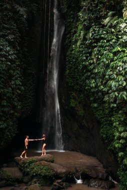 Şelalede aşık bir çift. Balayı gezisi. Bali 'de şelalede güzel bir çift. Çift Endonezya 'da seyahat ediyor. Tatildeki mutlu çift. Düğün gezisi. Uzayı kopyala Dikey fotoğraf