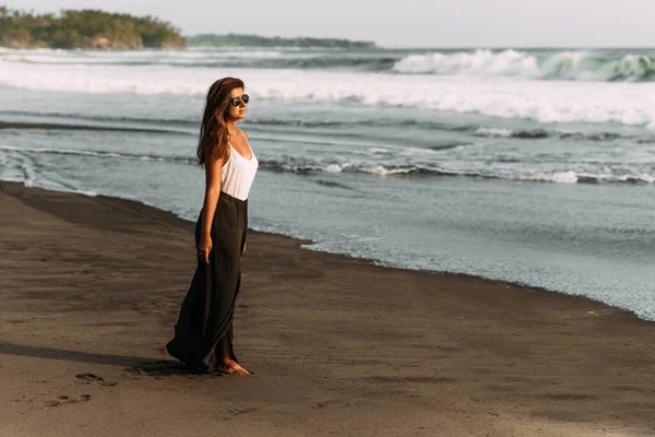 Beautiful woman model by the sea. Portrait of happy young woman smiling at sea. Beautiful young brunette on a tropical beach. Beautiful woman meets the sunset on the beach. Copy space