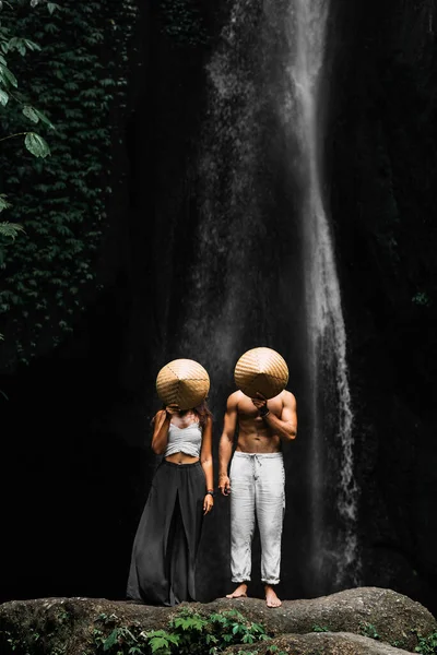 Пара Стоїть Біля Водоспаду Закриває Обличчя Рисовими Ковпаками Чоловік Жінка — стокове фото