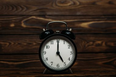 Ahşap bir arka planda saat. Saat öğleden sonra saat 5 'i gösteriyor. Saat sabahın 5: 00 'ini gösteriyor. Saat 05: 00 'i gösteren bir retro saat resmi. Boşluğu kopyala