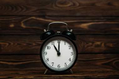 Ahşap bir arka planda saat. Saat öğleden sonra saat 11 'i göstermektedir. Saat sabah saat 11: 00 'i gösteriyor. Saat 11: 00 'i gösteren bir retro saat resmi. Boşluğu kopyala