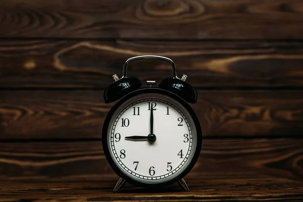 Clock on a wooden background. The clock shows the time of nine o\'clock in the afternoon. The clock shows the time of nine o\'clock in the morning. An image of a retro clock showing 09:00 pm/am. Copy space