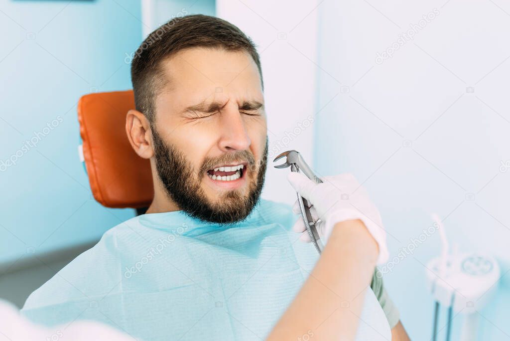 A man treats his teeth at the dentist. Dental examination at the dentist. Dental care. A man is afraid to treat his teeth. Fear of treating teeth. Tooth extraction at the dentist's office. Copy space