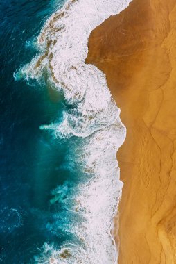 Güzel deniz dalgası. Güzel sarı kumsalı ve turkuaz denizi olan temiz bir sahil, dikey fotoğraf. Güzel deniz manzarası, yükseklikten manzara. Güzel kumlu plaj, manzaralı. Okyanus ve sahil. Boşluğu kopyala