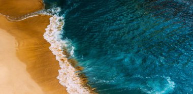 Endonezya 'daki Nusa Penida adasındaki Kelingking plajındaki mavi okyanus dalgalarının hava manzarası. Mavi denizi olan güzel kumlu bir sahil. Güzel dalgaları olan ıssız kumlu bir sahil. Endonezya plajları. Boşluğu kopyala