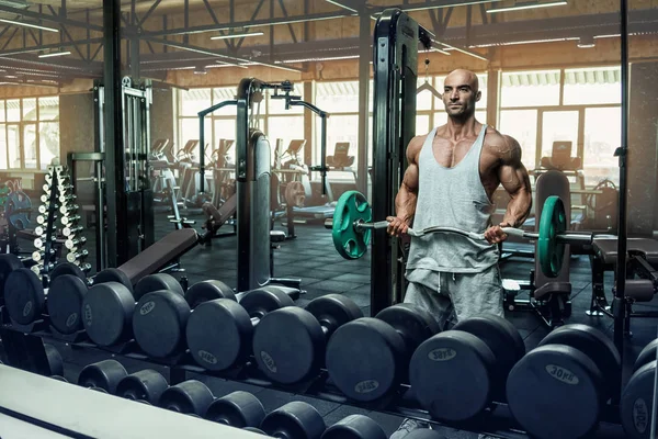 Jovem atleta bonito fisiculturista halterofilista com um corpo ideal, depois de treinar poses na frente da câmera, músculos abdominais, bíceps tríceps. Em sportswear . — Fotografia de Stock