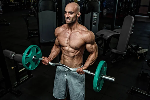 Jonge knappe sportman bodybuilder gewichtheffer met een ideaal lichaam, na coaching poseert voor de camera, buikspieren, biceps triceps. In sportkleding. — Stockfoto