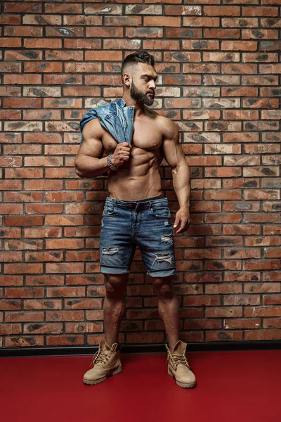 Portret van sterke gezonde knappe atletische man fitness model poseren in de buurt van de muur — Stockfoto