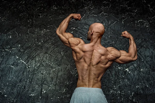 Porträt eines starken, gesunden, athletischen Mannes Fitnessmodel posiert in der Nähe einer dunklen Mauer — Stockfoto