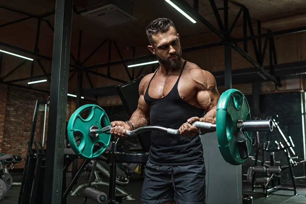 Jovem atleta bonito fisiculturista halterofilista com um corpo ideal, depois de treinar poses na frente da câmera, músculos abdominais, bíceps tríceps. Em sportswear . — Fotografia de Stock