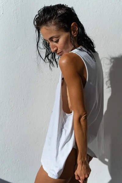 pretty brunette wearing tank top. summer photo of a beautiful tanned girl in a tank top. athletic girl posing on a white background in a sports T-shirt