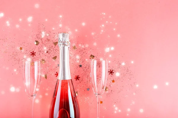 Julkoncept. Rosa champagne, tomtebloss och ett par glas. Stockfoto