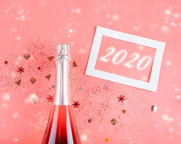Julkoncept. Rosa champagne, glitter på rosa bakgrund Stockbild