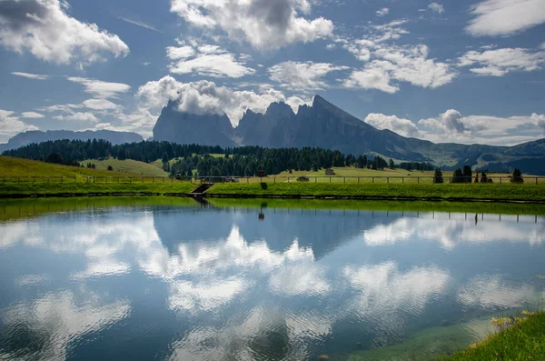 Sassolungo ve Langkofel dağ grubunun yansıması ve Picturesque gölündeki bulutlu mavi gökyüzü. Sassolungo ve Langkofel dağ grubuyla Alpe di Siusi veya Seiser Alm, Güney Tyrol, İtalya