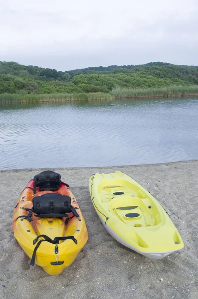 Two types of kayak two-seat sit-on-top  on the sandy bank of the