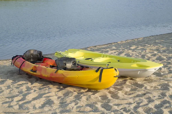 Two types of kayak two-seat sit-on-top  on the sandy bank of the