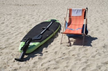 Tahta, kürek, güverte sandalyesi ve kumsalda güneşli havada pompa