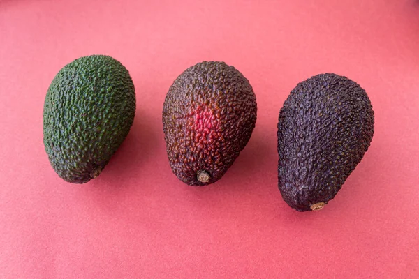 Aguacate en diferentes grados de madurez sobre fondo rojo. Estilo laico plano. De cerca. Lugar para el texto Imágenes De Stock Sin Royalties Gratis