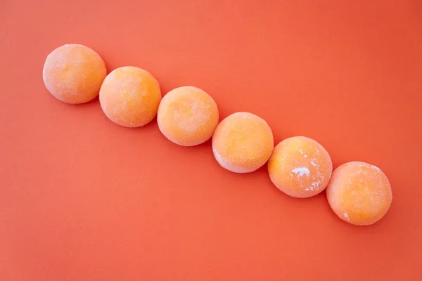 Mochi mit Mango. Hochwertiges Eis in süßem Reisteig, traditioneller japanischer Nachtisch. Glutenfrei. Orange auf Pastellblau — Stockfoto