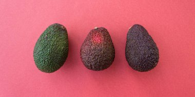 Kırmızı arka planda farklı olgunlukta Avokado bayrağı. Düz yatış stili. Kapatın. Metin için yer