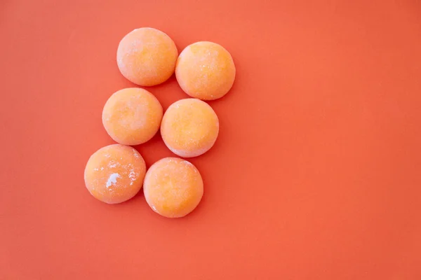 Mochi mit Mango. Hochwertiges Eis in süßem Reisteig, traditioneller japanischer Nachtisch. Glutenfrei. Orange auf Pastellblau — Stockfoto