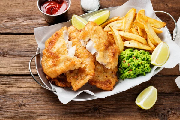 British Traditional Fish and chips with mashed peas and sauce.